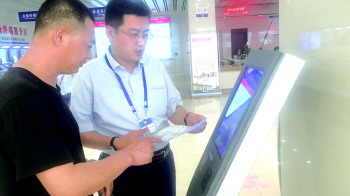 工作人员正在指导市民使用叫号机